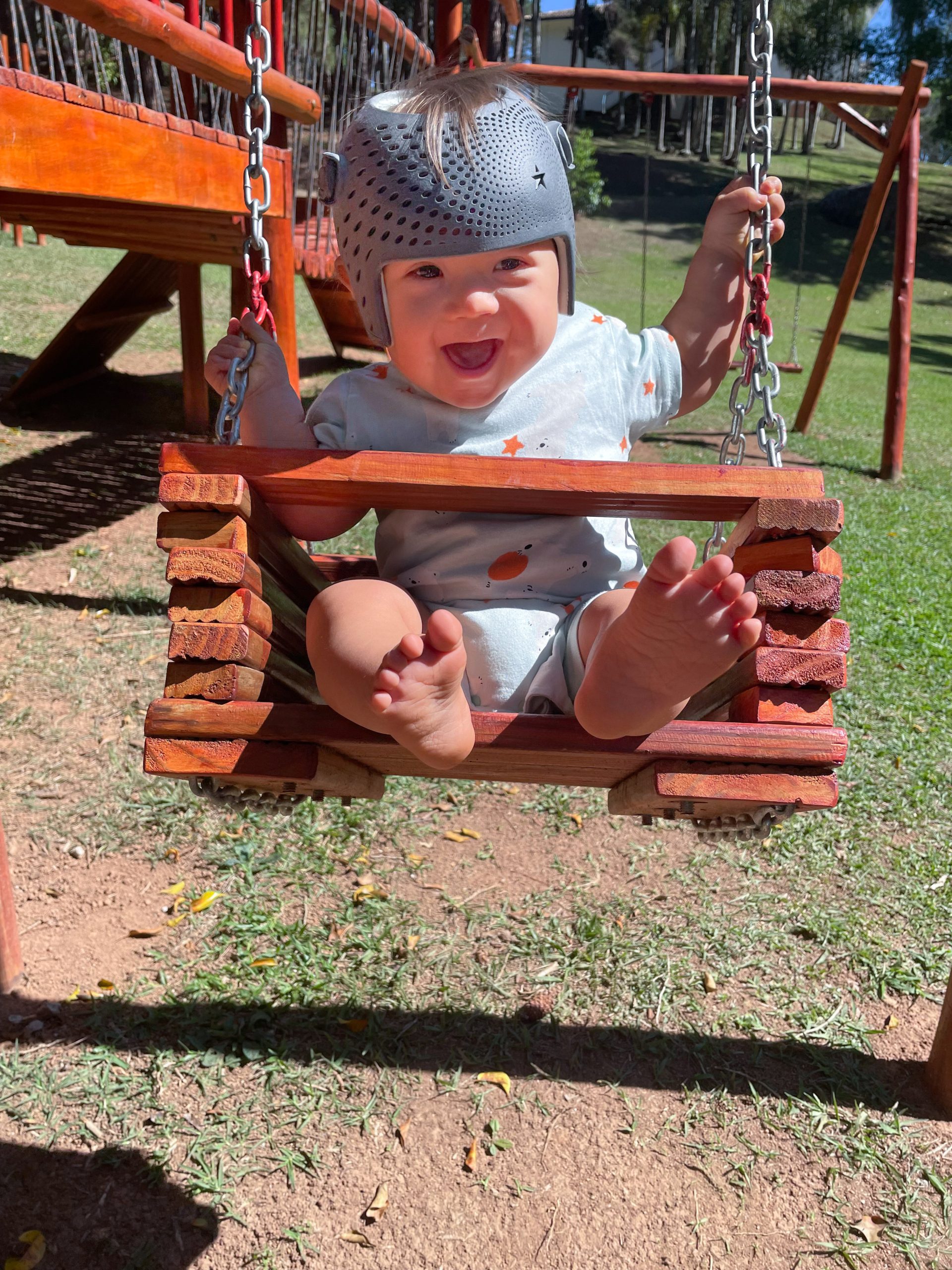 child on a swing wearing a cranial helmet